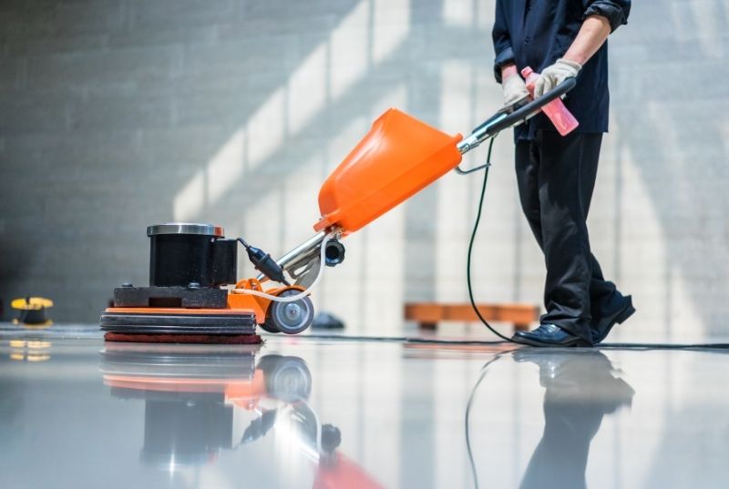 Person polishing a marble tile floor with a machine for a commercial cleaning services