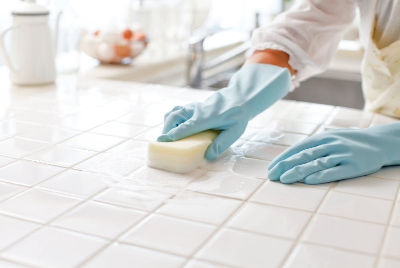 Person deep cleaning a tiled kitchen bench in Newcastle