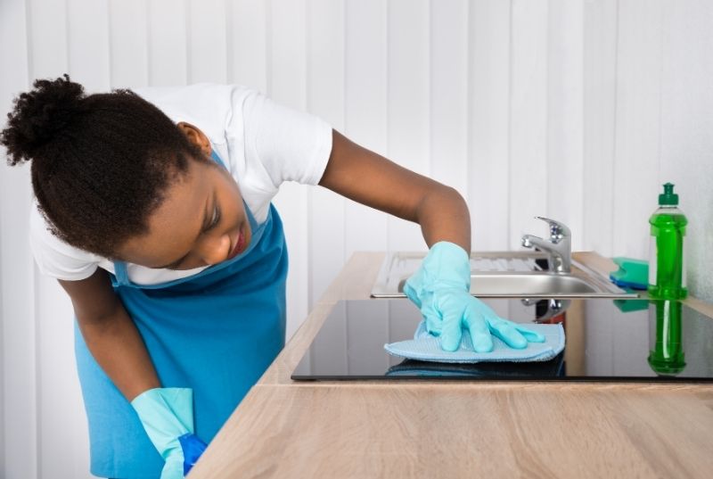 Maid wiping a glass cook top with a cloth