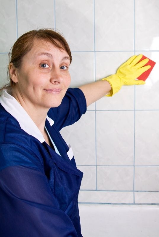 Maid wiping bathroom walls