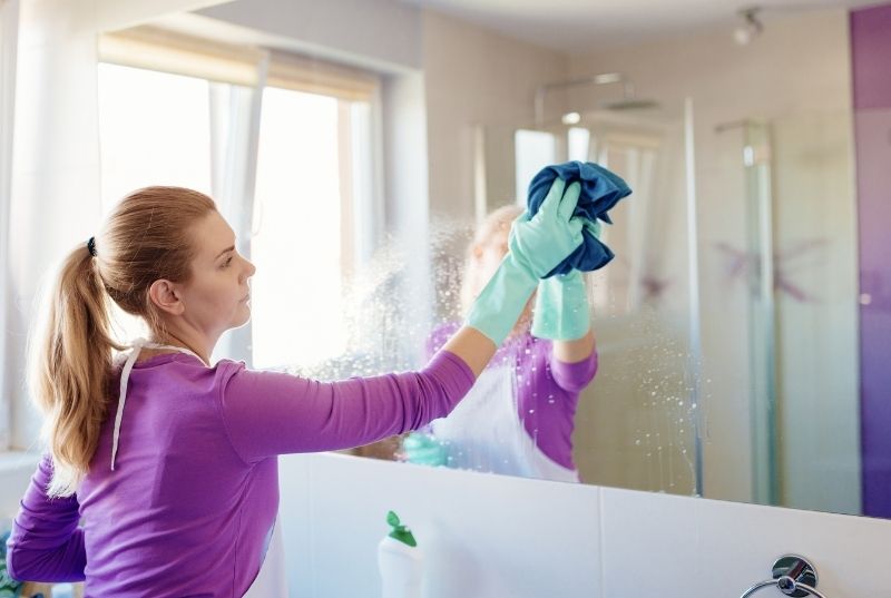 Maid wiping a bathroom mirror for a house one-off cleaning services