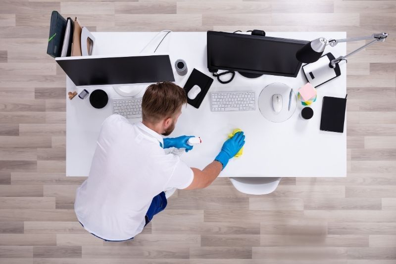 Picture taken from above of a cleaner wiping an office desk