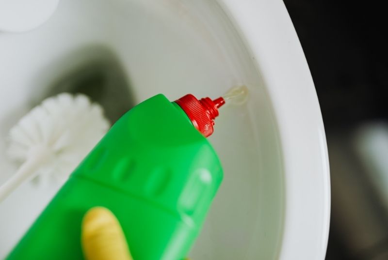 Person using a toilet cleaning product and a brush for a Central Coast deep clean services