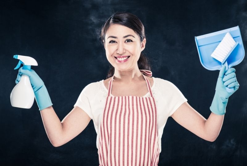 Cleaning Central Coast staff member a dustpan and brush in one hand and a cleaning product in the other one